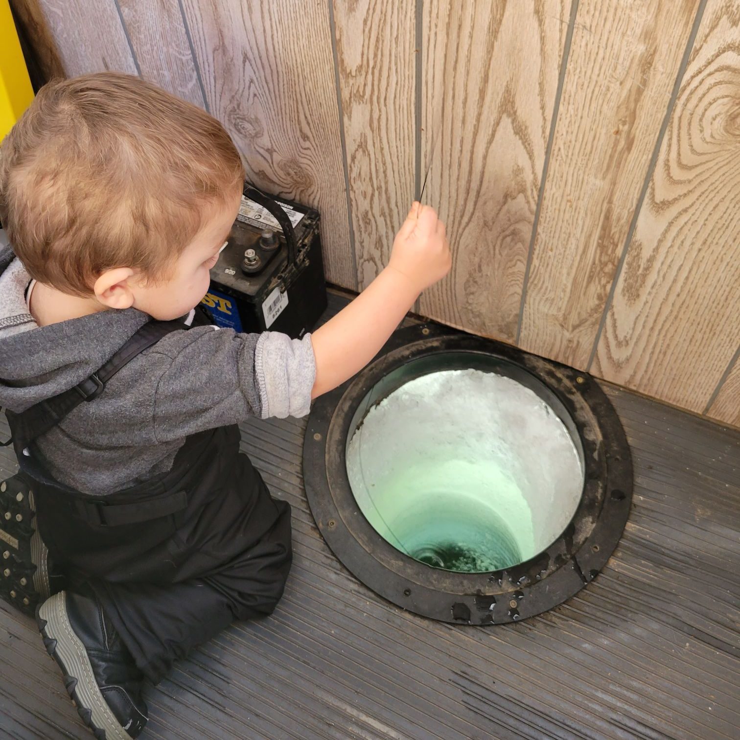 toddler jigging a rattle reel in a fish house
